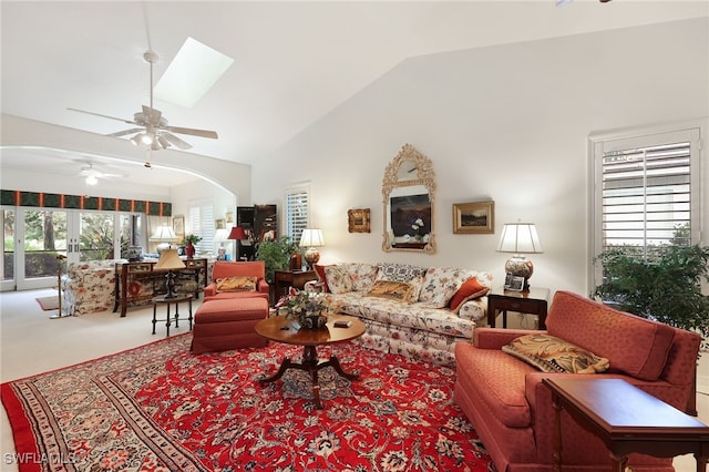 carpeted living room featuring ceiling fan, a skylight, high vaulted ceiling, and a healthy amount of sunlight