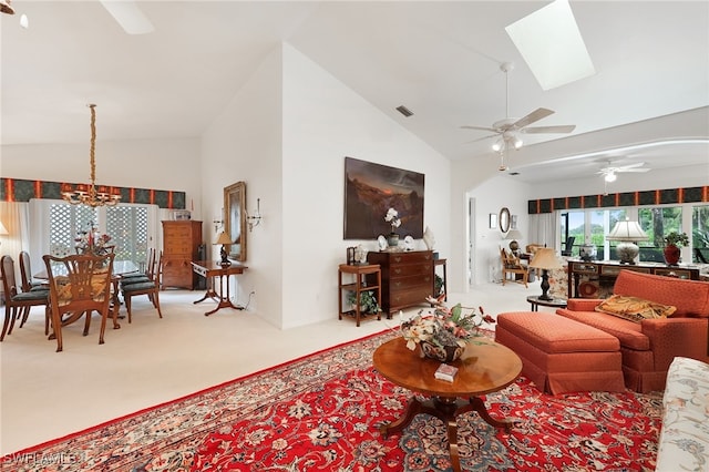 living room with ceiling fan with notable chandelier, high vaulted ceiling, a skylight, and light carpet