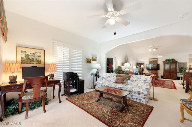 carpeted living room with ceiling fan and arched walkways