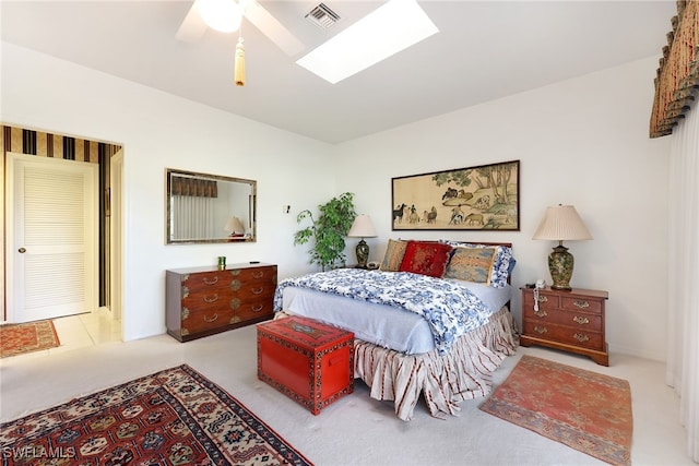carpeted bedroom with visible vents, a skylight, and a ceiling fan