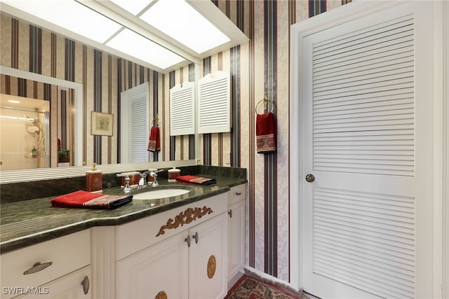 bathroom featuring vanity and wallpapered walls