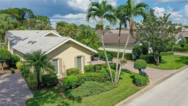 exterior space featuring stucco siding, a tiled roof, and a front lawn