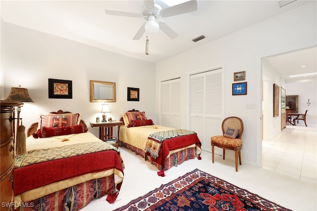 carpeted bedroom with visible vents, baseboards, a ceiling fan, and two closets