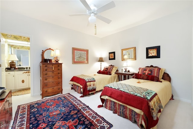 bedroom with ensuite bathroom, light colored carpet, baseboards, and a ceiling fan
