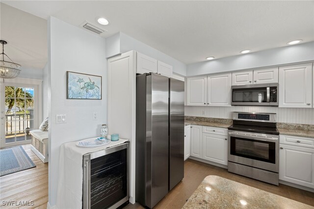 3311 Twin Lakes Ln, Sanibel, FL 33957 - kitchen featuring appliances with stainless steel finishes, beverage cooler, wood finished floors, and white cabinets