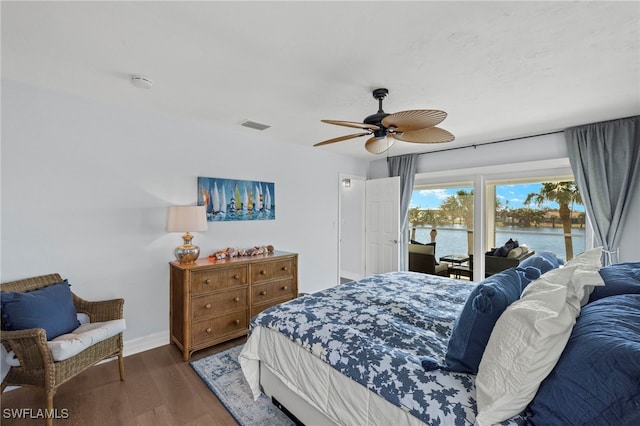 bedroom featuring access to outside, a water view, ceiling fan, and dark wood-type flooring