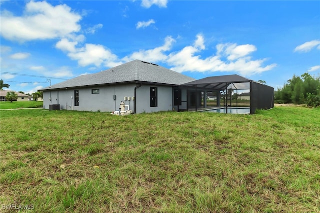 rear view of property with glass enclosure and a yard