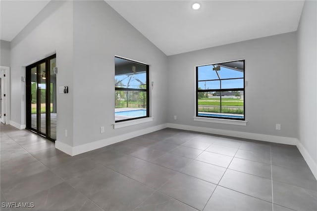 unfurnished room featuring vaulted ceiling, a healthy amount of sunlight, and tile patterned floors