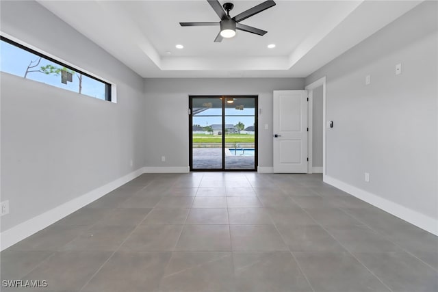 unfurnished room with a raised ceiling, ceiling fan, and tile patterned floors