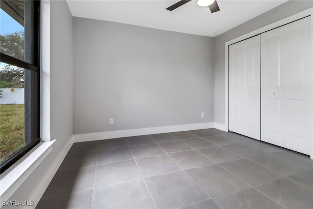 unfurnished bedroom with ceiling fan, a closet, and dark tile patterned floors