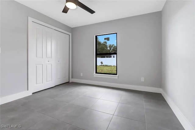 unfurnished bedroom with ceiling fan, a closet, and tile patterned flooring