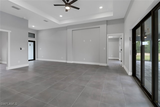 spare room with ceiling fan and a raised ceiling