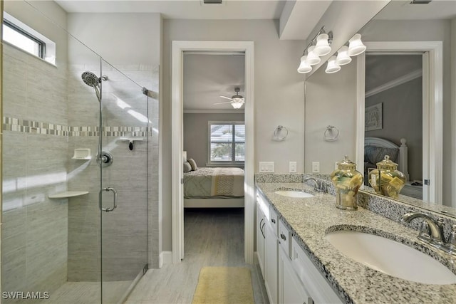 bathroom with ceiling fan, vanity, a shower with door, and crown molding