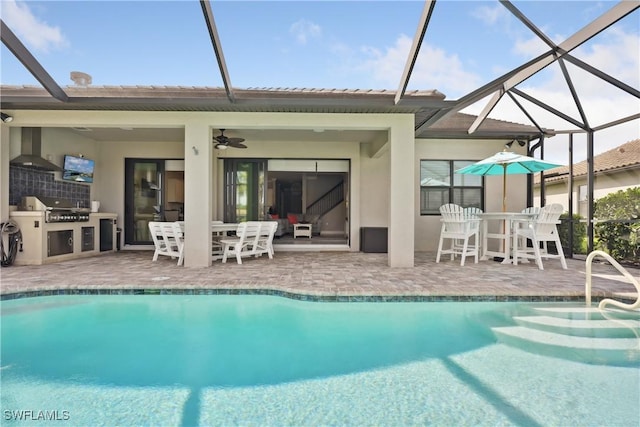 rear view of property featuring ceiling fan, exterior kitchen, a patio area, and glass enclosure