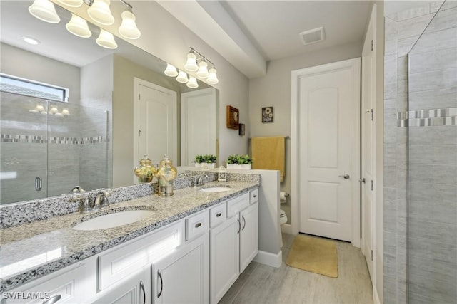 bathroom with a shower with shower door, vanity, and toilet