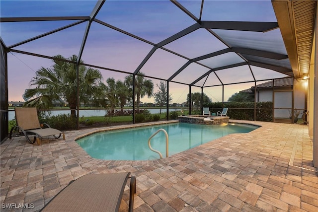 pool at dusk featuring a lanai, a patio area, and an in ground hot tub