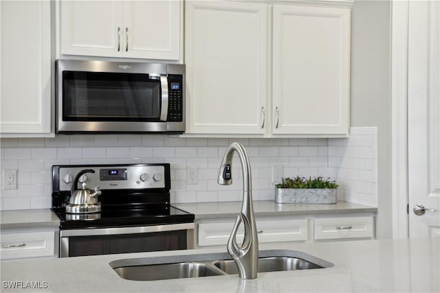 kitchen featuring decorative backsplash, white cabinets, and stainless steel appliances