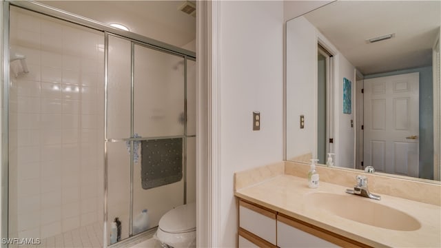 bathroom featuring toilet, a shower with shower door, and vanity