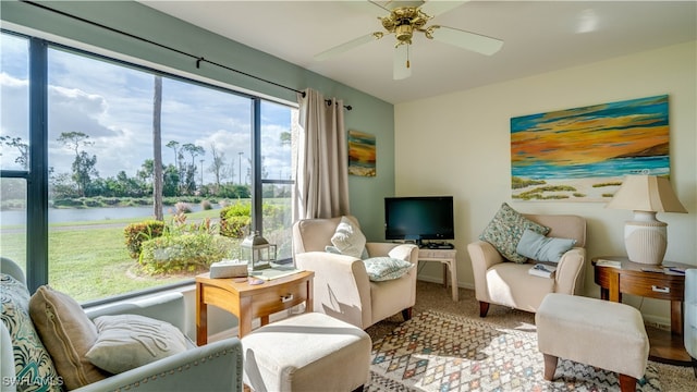 sitting room with a water view, ceiling fan, and carpet floors