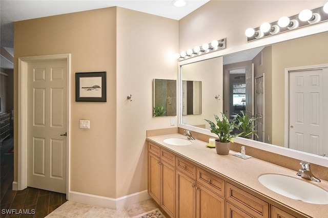 full bathroom with a sink, baseboards, and double vanity