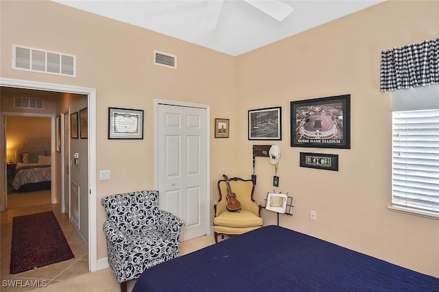 bedroom with a closet, light tile patterned floors, and ceiling fan