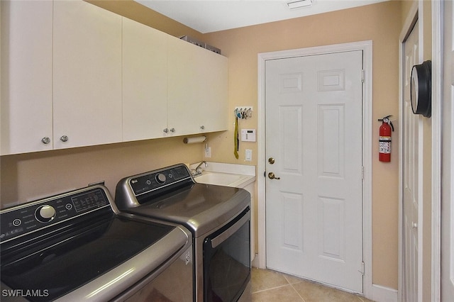 laundry area featuring light tile patterned flooring, washing machine and dryer, and cabinets