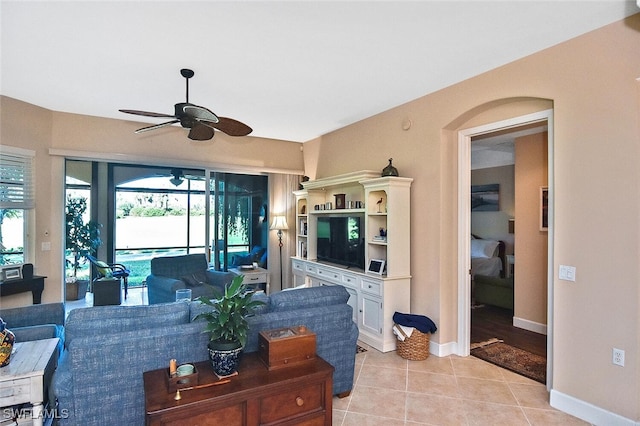 living area with light tile patterned floors, ceiling fan, a sunroom, and baseboards