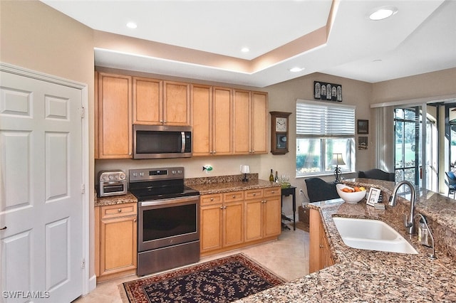 kitchen featuring stainless steel appliances, dark stone counters, sink, and light tile patterned floors