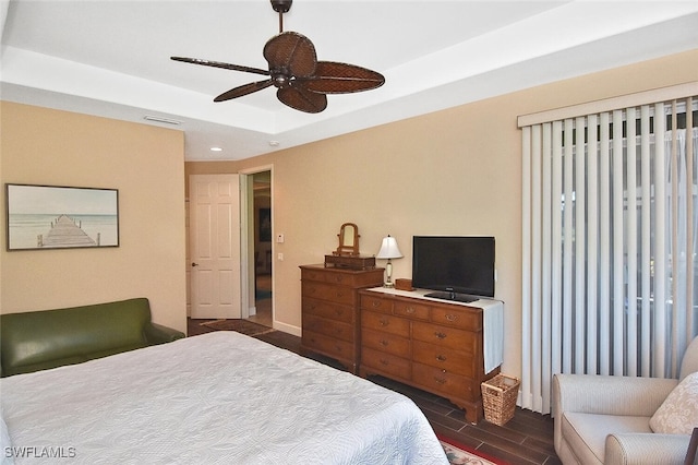 bedroom with dark hardwood / wood-style floors, a tray ceiling, and ceiling fan