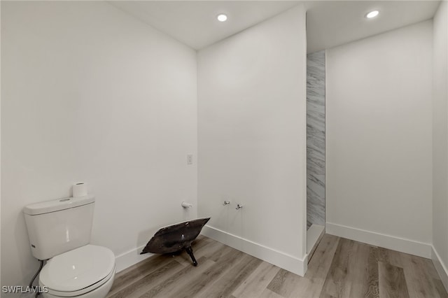 bathroom featuring hardwood / wood-style floors, toilet, and a shower