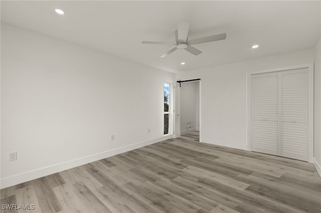 unfurnished bedroom featuring ceiling fan, a closet, and light wood-type flooring