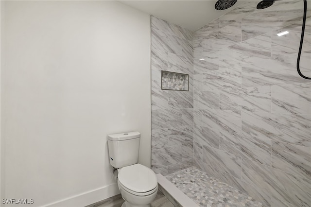 bathroom featuring tiled shower and toilet