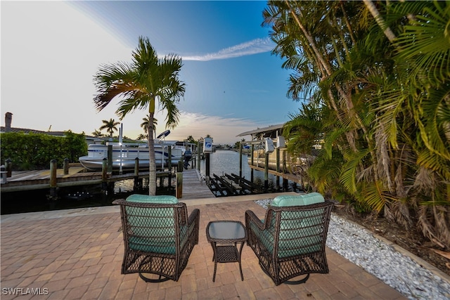 patio terrace at dusk featuring a boat dock and a water view