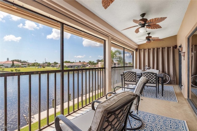 sunroom / solarium with a water view and ceiling fan