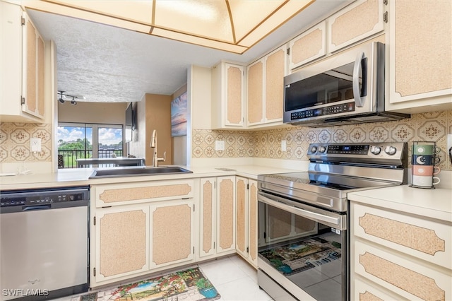 kitchen featuring tasteful backsplash, appliances with stainless steel finishes, sink, and light tile patterned floors