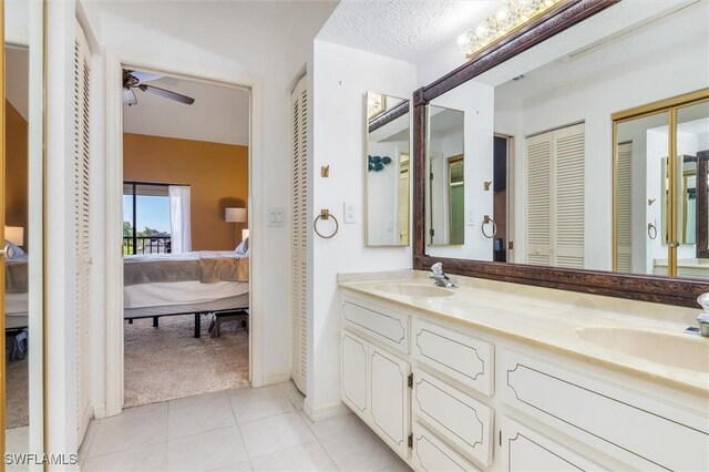 bathroom featuring ceiling fan, vanity, tile patterned flooring, and a textured ceiling