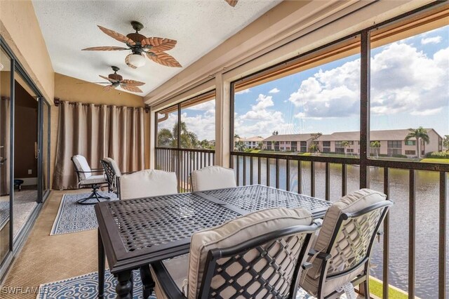 sunroom / solarium with a water view, ceiling fan, and vaulted ceiling