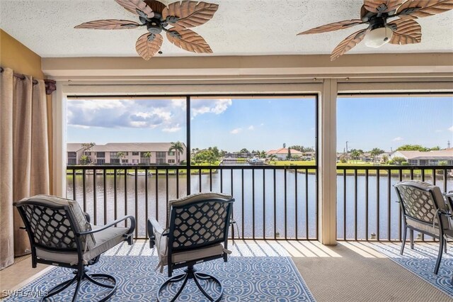 sunroom / solarium with a water view and ceiling fan