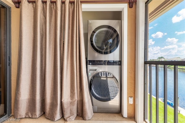 washroom with stacked washer and clothes dryer and a water view