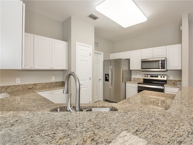 kitchen featuring appliances with stainless steel finishes, light stone countertops, sink, and white cabinets