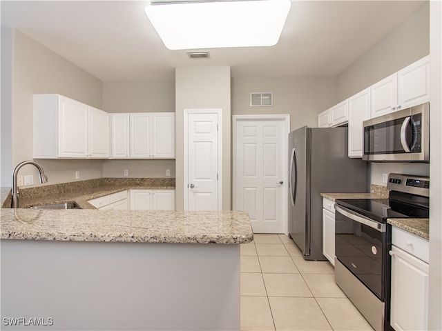 kitchen featuring light tile patterned flooring, sink, light stone counters, white cabinets, and appliances with stainless steel finishes