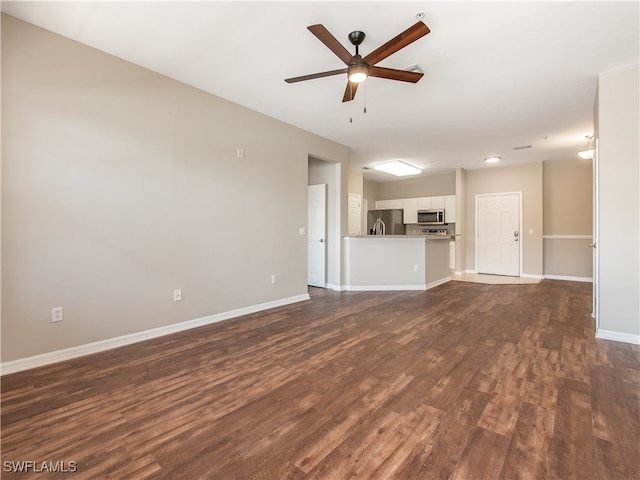 unfurnished living room featuring ceiling fan and dark wood-type flooring