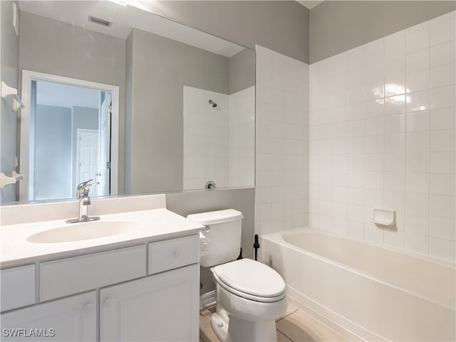 full bathroom featuring tiled shower / bath, vanity, and toilet