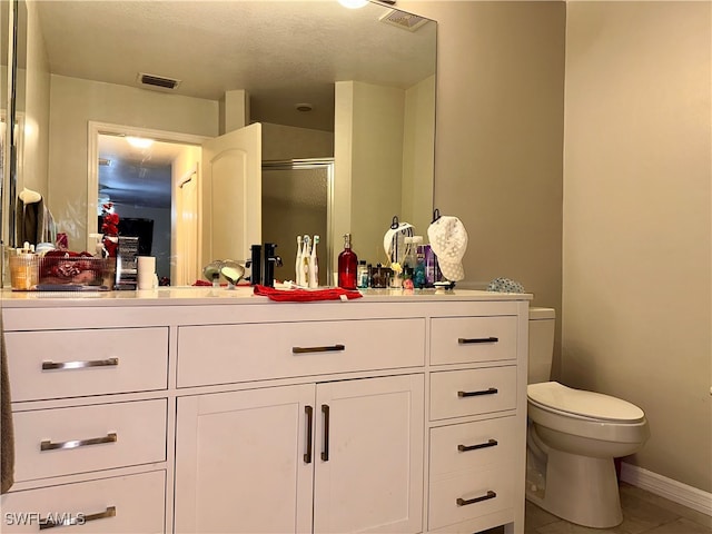 bathroom featuring a shower with door, tile patterned flooring, a textured ceiling, vanity, and toilet