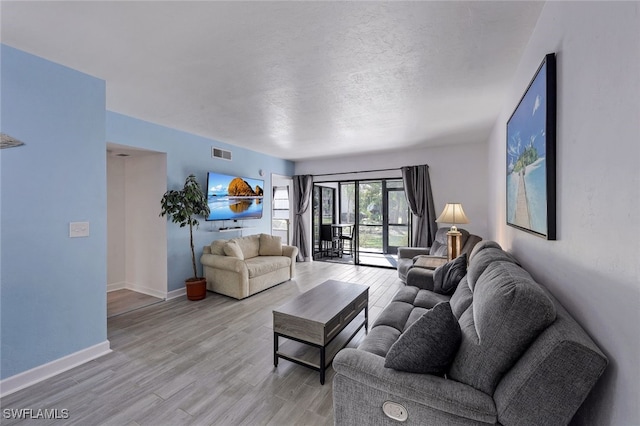 living room with a textured ceiling and light wood-type flooring