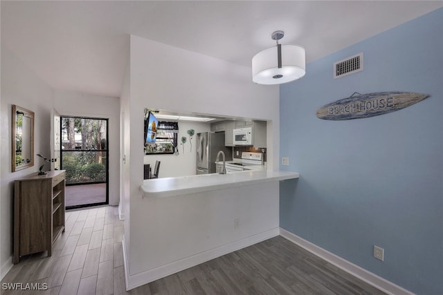 kitchen featuring white appliances, dark hardwood / wood-style flooring, and kitchen peninsula