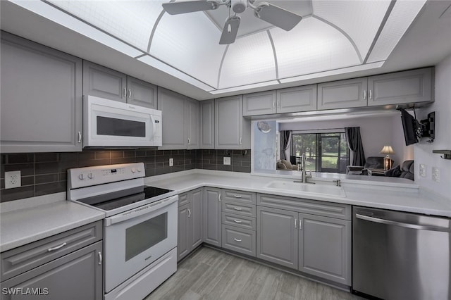 kitchen featuring gray cabinets, white appliances, light hardwood / wood-style flooring, and sink