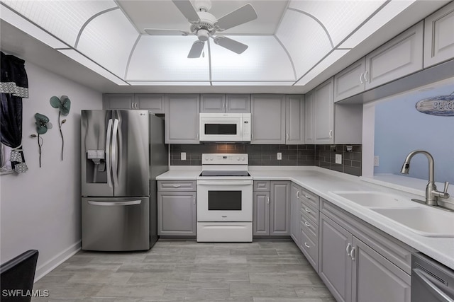 kitchen featuring gray cabinetry, backsplash, stainless steel appliances, ceiling fan, and sink