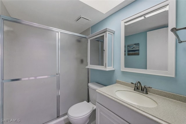 bathroom featuring vanity, a shower with shower door, and toilet