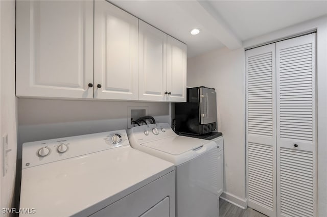 clothes washing area with cabinets, wood-type flooring, and washing machine and dryer